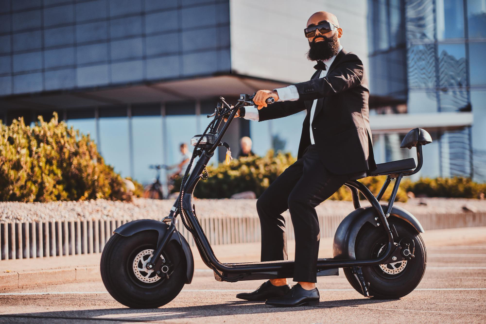 smart attractive businessman is sitting his electro scooter while posing photographer